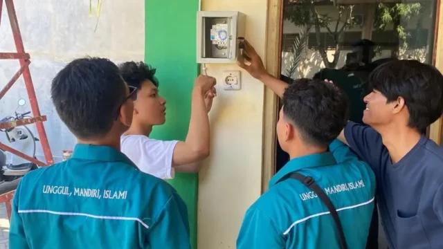 Mahasiswa KKN UMG Kelompok 24 memasang lampu PJU otomatis dengan sensor LDR di Desa Dooro, Cerme, Gresik. Lampu menyala saat gelap, padam saat terang.
